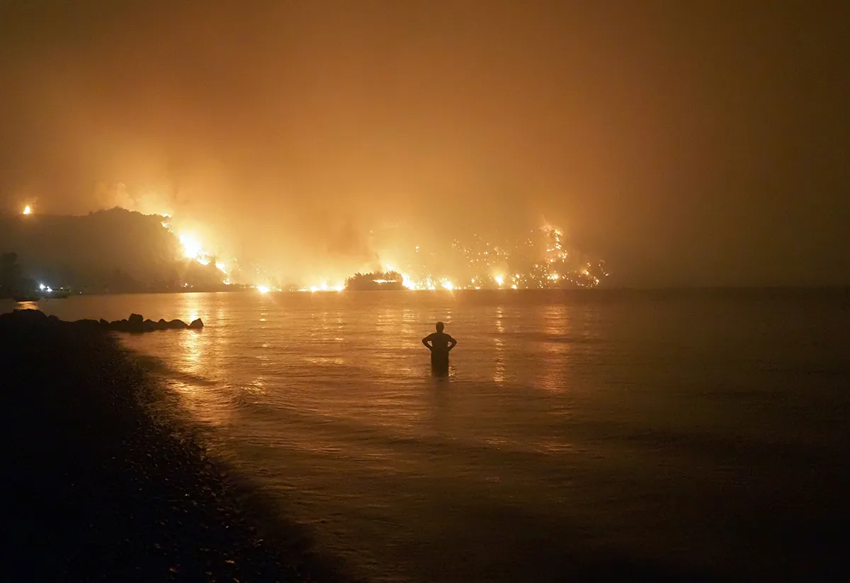 Photo by Thodoris Nikolaou/AP/Shutterstock (12253990a) Dated, a man watches as wildfires approach Kochyli beach near Limni village on the island of Evia, about 160 kilometers (100 miles) north of Athens, Greece. A new massive United Nations science report is scheduled for release Monday Aug. 9, 2021, reporting on the impact of global warming due to humans UN Climate Report, Limni, Greece - 06 Aug 2021