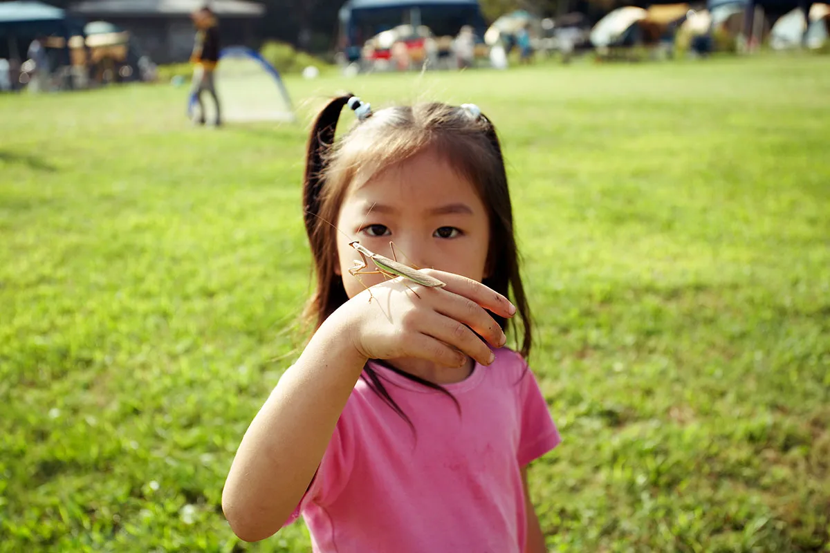 A young child with a grasshopper on her hand