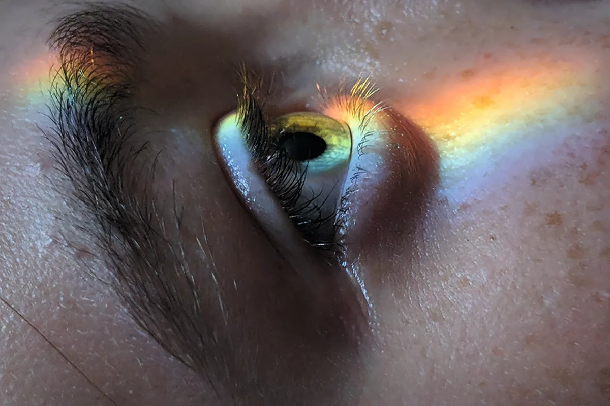 A rainbow beam of light projected onto a person's face © Getty Images