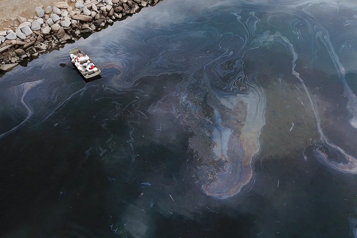 TOPSHOT - This aerial picture taken on October 4, 2021 shows environmental response crews cleaning up oil that flowed near the Talbert marsh and Santa Ana River mouth, creating a sheen on the water after an oil spill in the Pacific Ocean in Huntington Beach, California. (Photo by Patrick T. FALLON / AFP) (Photo by PATRICK T. FALLON/AFP via Getty Images)