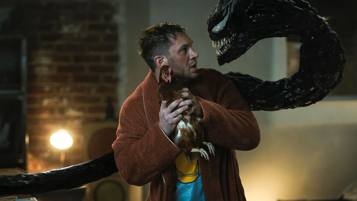Tom Hardy as Eddie Brock, holding a chicken and talking to the alien symbiote Venom © Sony Pictures Releasing/PA Media Select