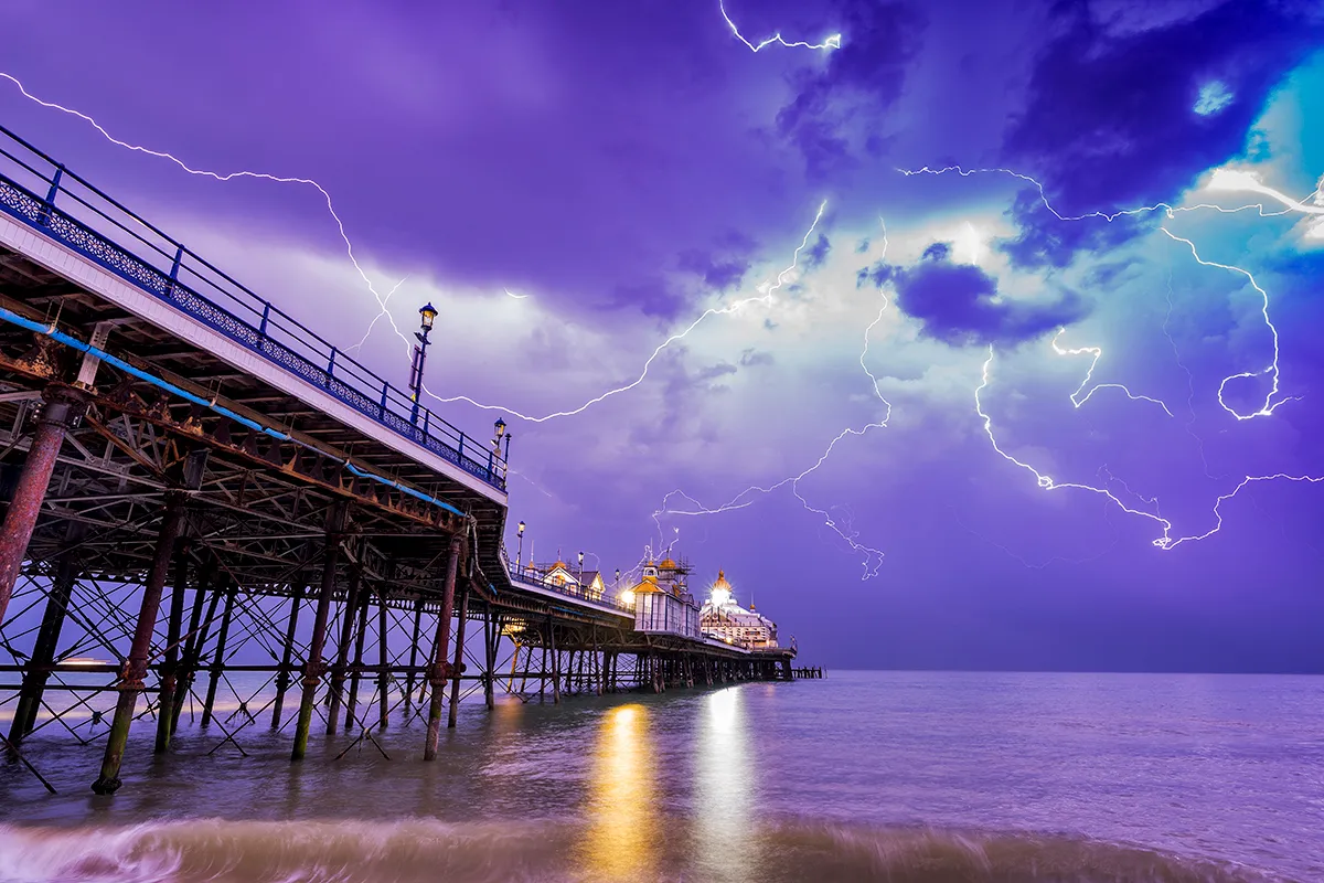 A complex array of lightning channels streak across the sky above Eastbourne Pier on the south coast of England during an overnight thunderstorm. Thunder occurs as a result of intense heating of air surrounding the lightning channel. The heated air expands rapidly, which sets up shock waves that radiate outwards in the form of sound waves that we hear as thunder. When a bolt of lightning strikes close by, the thunder is sudden and may sound almost like an explosion, but with increasing distance the sound waves tend to disperse, leading to the rumbling sound that is perhaps more familiar. The sound waves from different parts of the lightning channel, at greater or lesser distances from the observer, take varying amounts of time to reach the observer, which also explains why thunder tends to last several seconds and why a single roll of thunder often comprises multiple peaks and troughs in volume. Thunder is typically audible up to about 16–24 km (10–15 miles) from the lightning, though this varies according to the atmospheric conditions. Photo by Simon Anderson