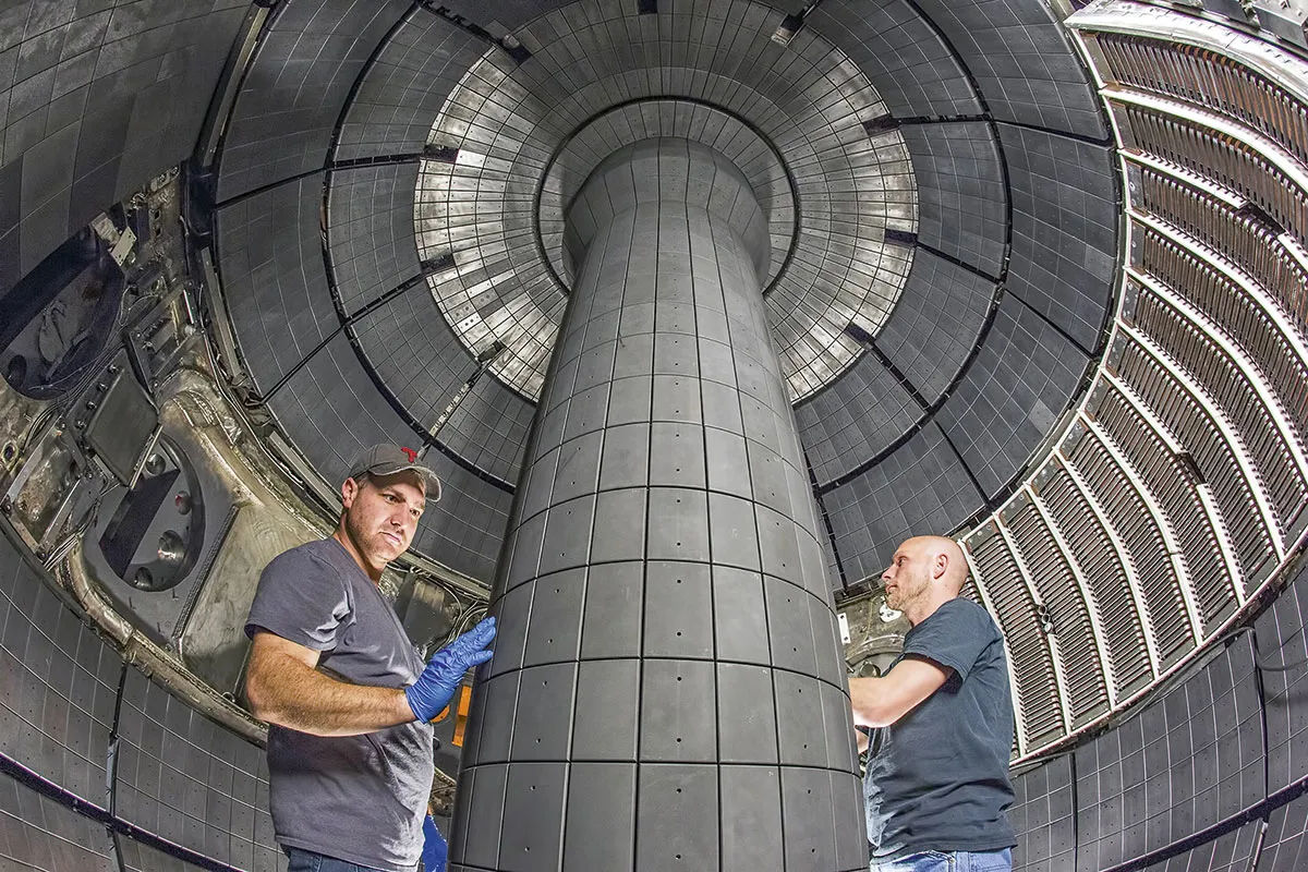 Two people working on the chamber inside the NSTX-U reactor © Elle Starkman/Princeton Plasma Physics Laboratory