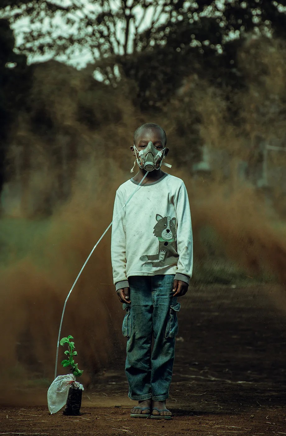 A young boy takes in air from the plant in this symbolic image taken in Kenya, while a sand storm brews in the background. The last breath by Kevin Ochieng Onyango, 2021. By courtesy of the photographer and Environmental Photographer of the Year 2021