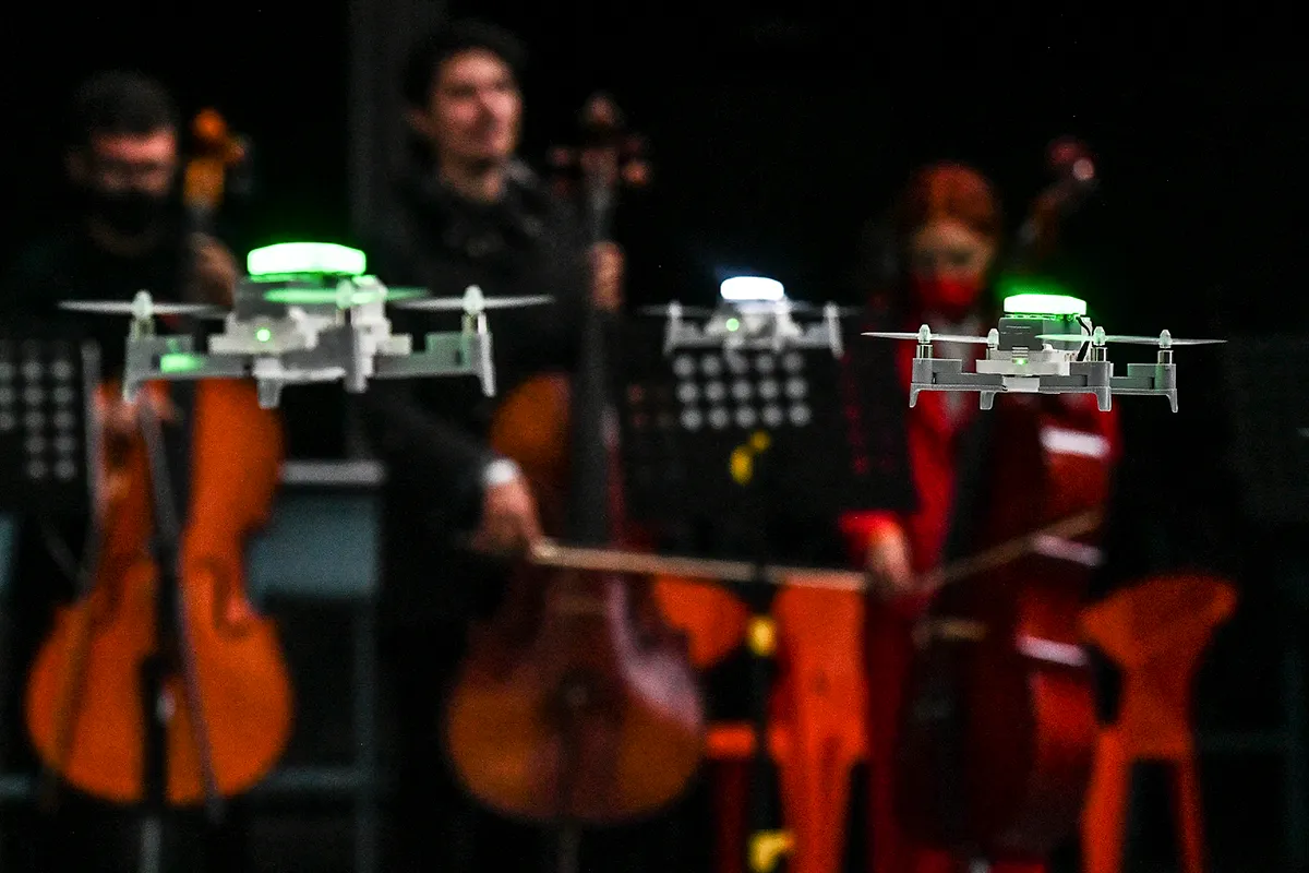 Musicians play as a squad of drones flies synchronized with the music during a drone show at Medellin's Tech Fest in Medellin, Colombia on November 26, 2021. (Photo by JOAQUIN SARMIENTO / AFP) (Photo by JOAQUIN SARMIENTO/AFP via Getty Images)