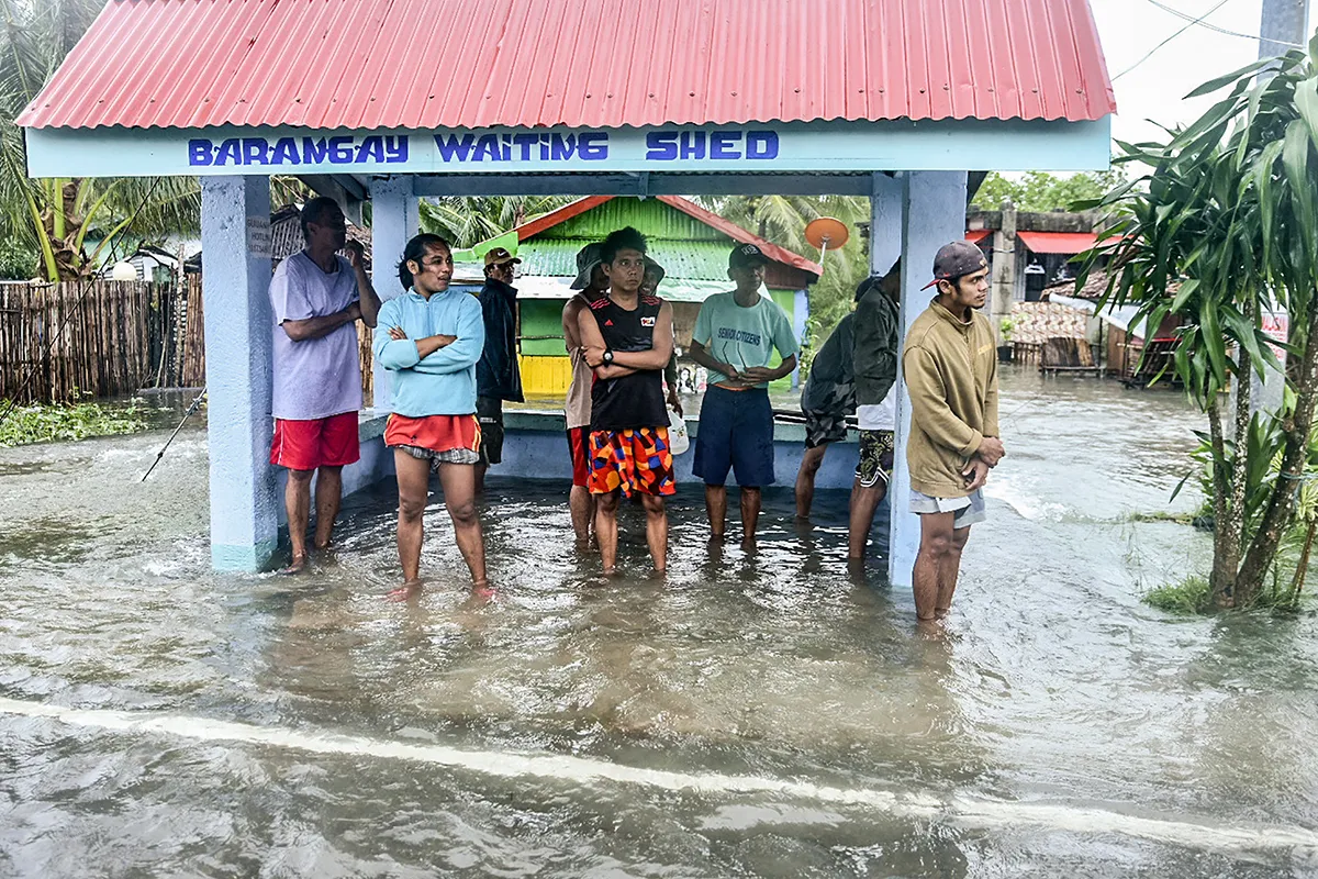 Residents stand in a flooded bus stop
