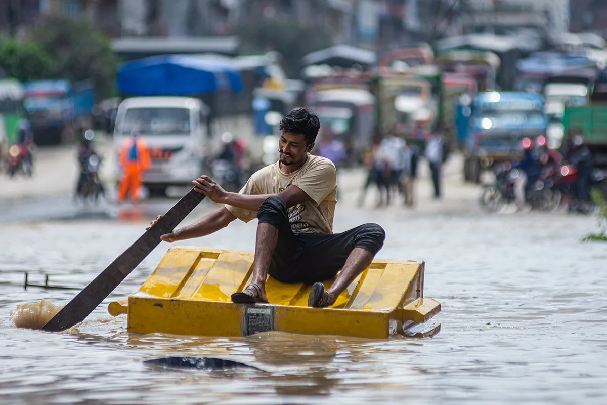 A man rides a makeshift raft in the middle of flooded road