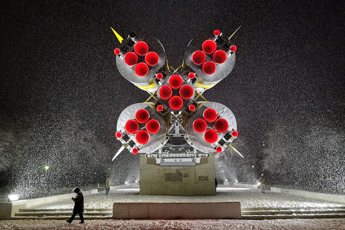 woman walks in front of a Soyuz rocket installed as a monument