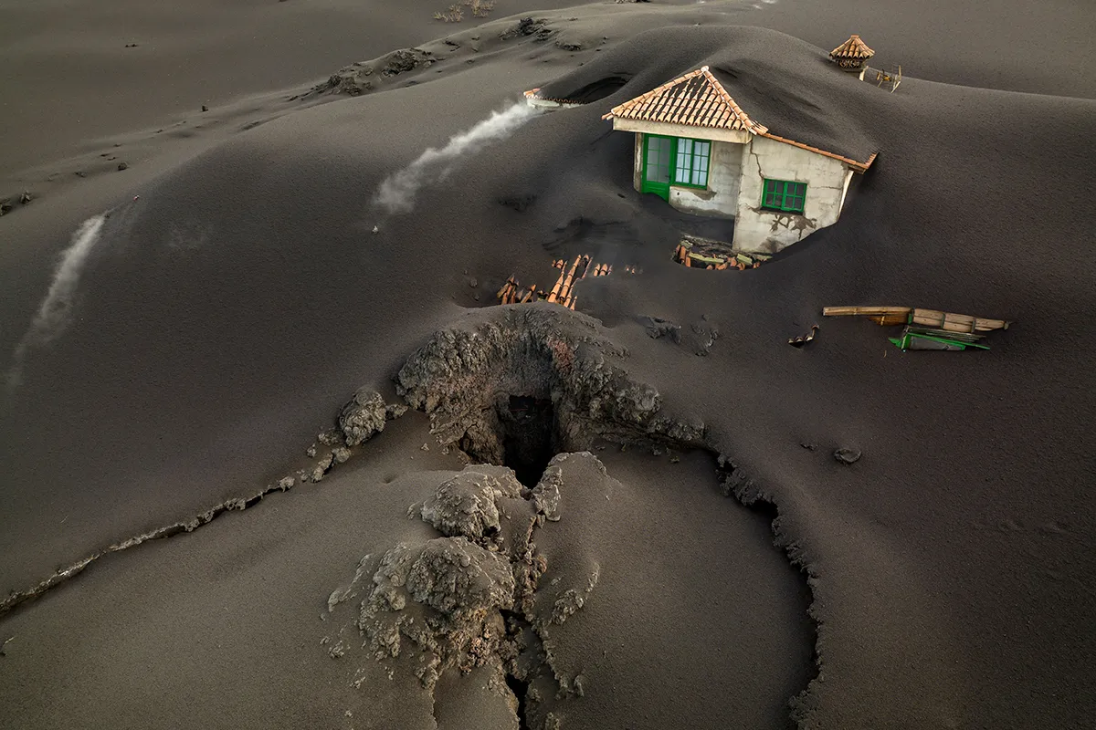 A fissure is seen next to a house covered with ash on the Canary island