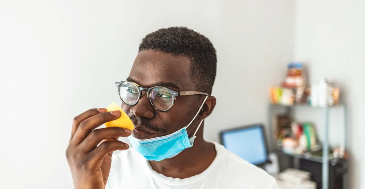 Man wearing protective face mask smelling a lemon