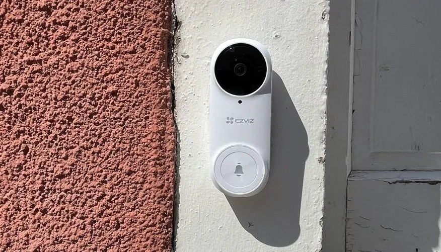 White smart doorbell on door frame in the sun from side angle