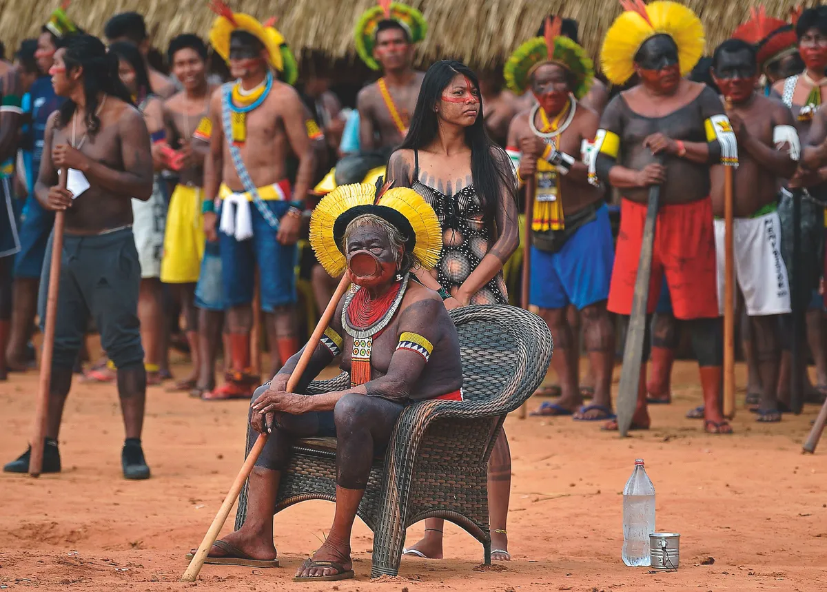 Indigenous leader Cacique Raoni Metuktire of the Kayapo tribe, watches as various tribes perform ceremonial dances for him, in Piaracu village, near Sao Jose do Xingu, Mato Grosso state, Brazil. Photo by CARL DE SOUZA/AFP via Getty Images