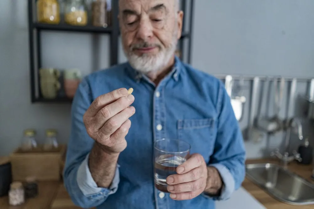 Older man holds onto pill and glass