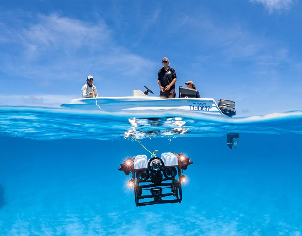An image of researchers deploying an underwater ROV into bright blue waters