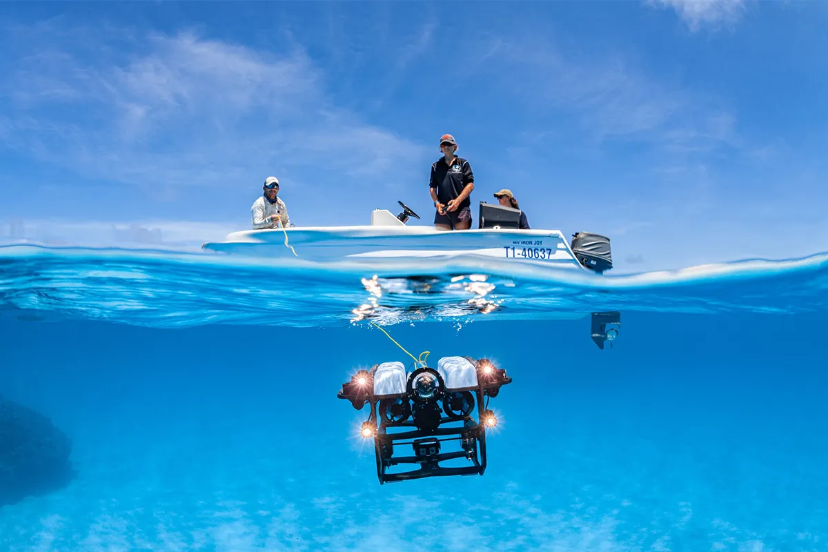An image of researchers deploying an underwater ROV into bright blue waters