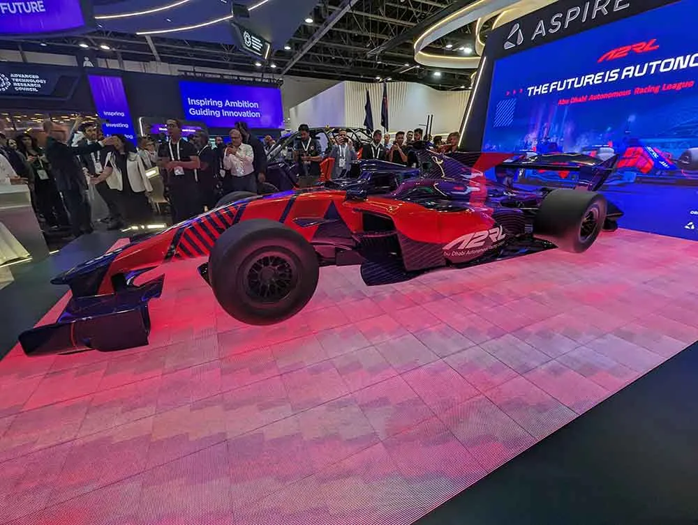 The new autonomous racing car for the Dallara Super Formula SF23 sat on stage with a crowd behind it.