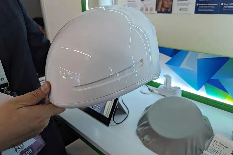 Person holds a white helmet designed to send signals to the brain to promote sleep.