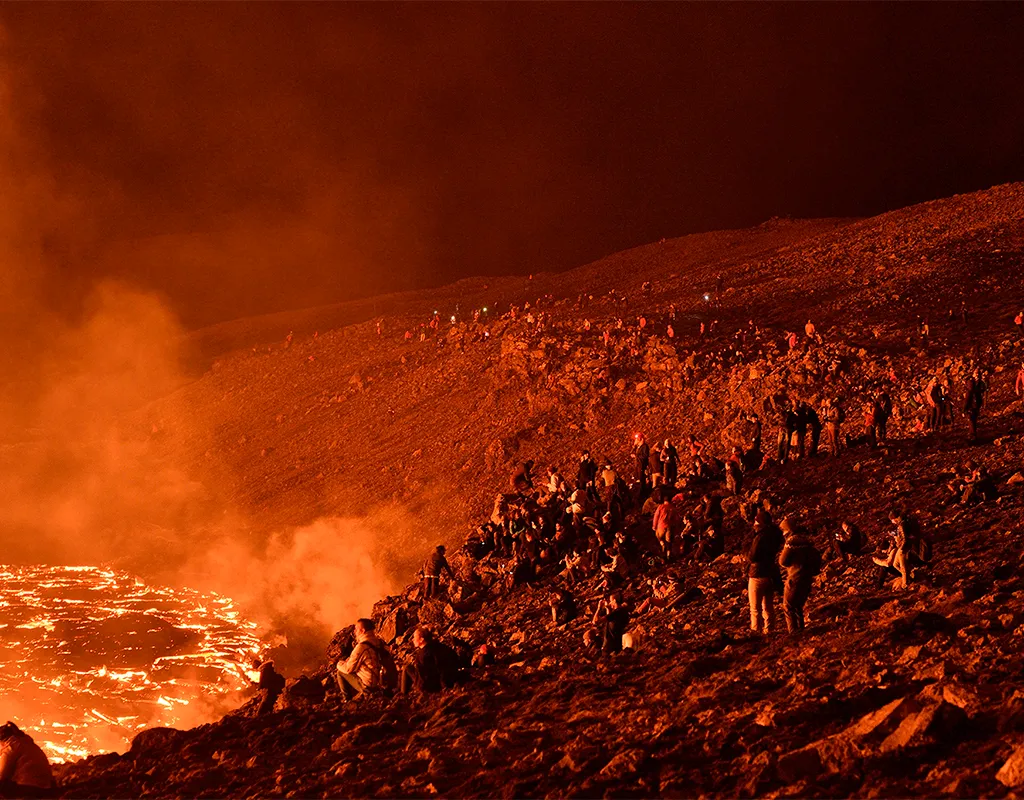 People watch lava flows from hillside