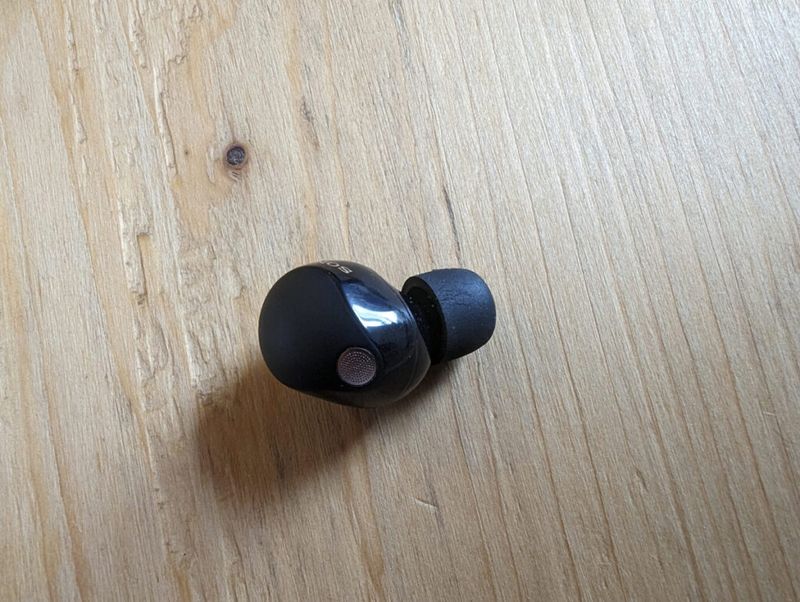Single earbud from the Sony WF-1000XM5 lying on table