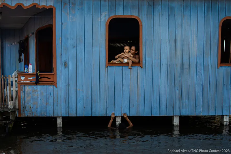 Dom nad powodzią Kobieta trzymająca dziecko przy oknie