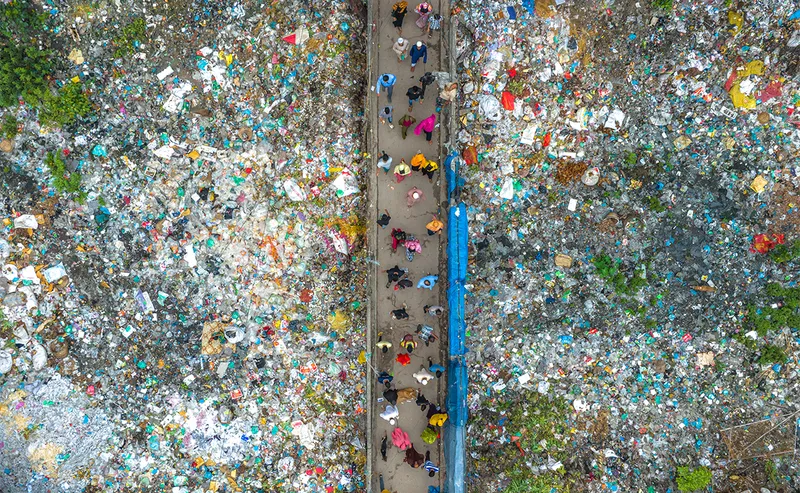 Aerial image of People walking through large mounds of trash