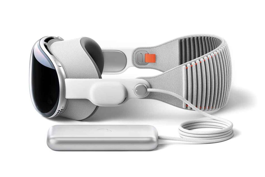 The Apple Vision Pro headset sat on a white background with a charger lined up next to it