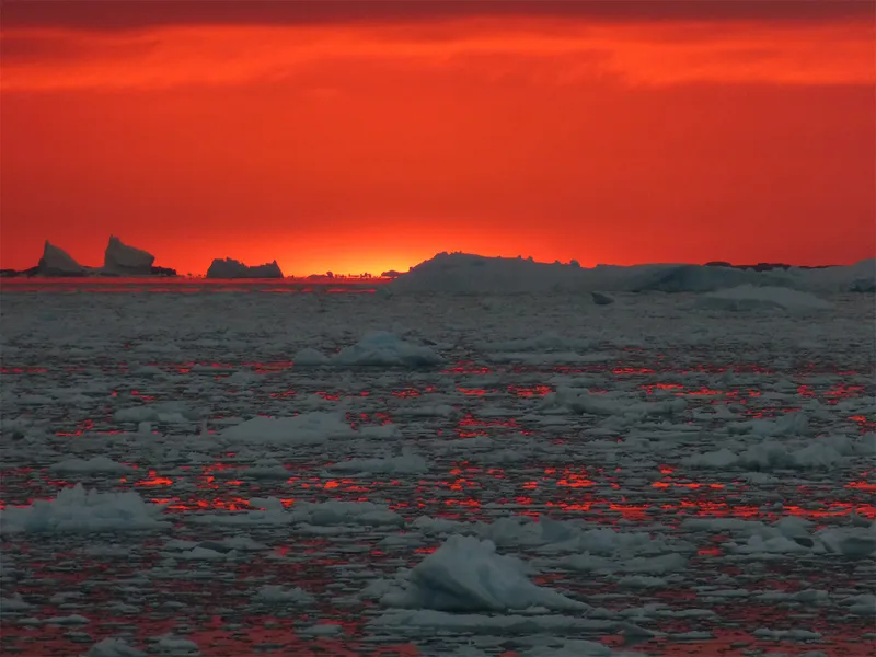 red sky over fields of grey icebergs