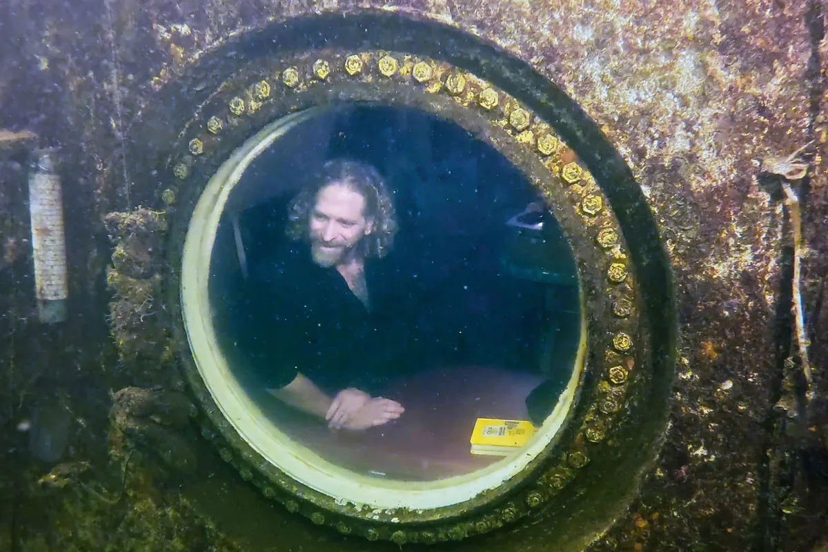 Joseph Dituri sitting by a window in an underwater lagoon.