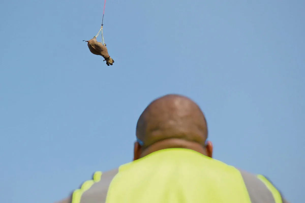 Man watches as a Rhino is airlifted by a helicopter.
