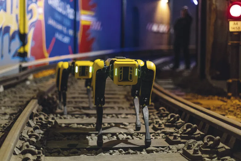 Two robotic dogs on an empty railway track.