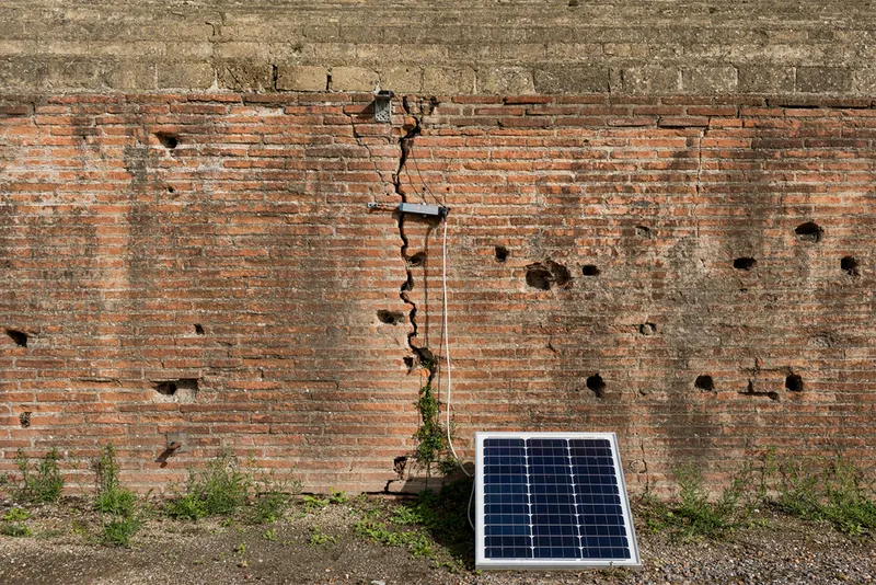 Cracked old wall with sensor and solar panel