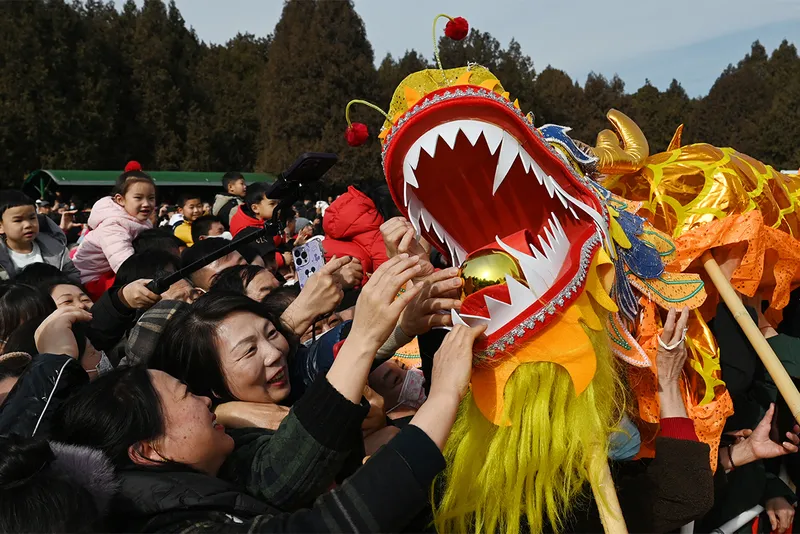 Woman puts a golden egg in the mouth of a dragon puppet