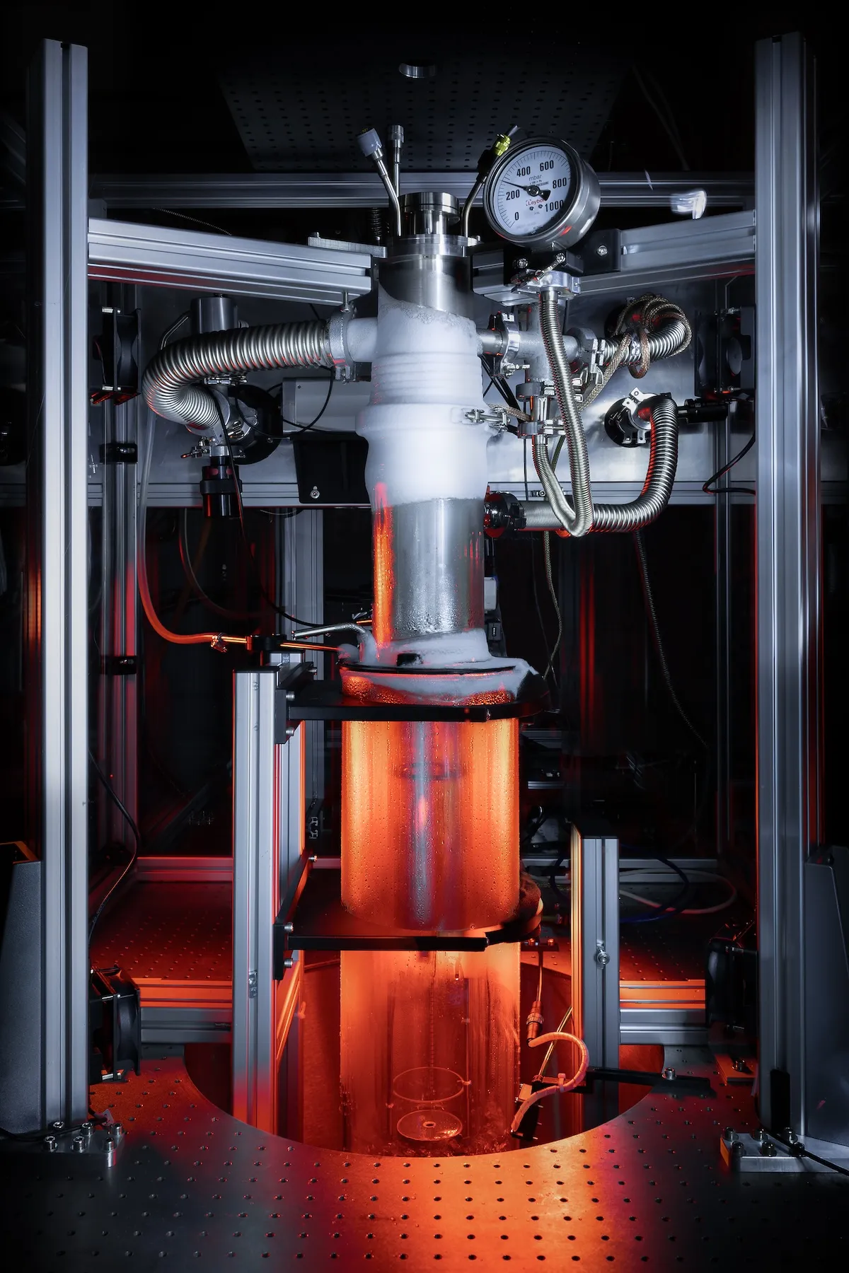 A tall device backlit in an orange and red light in the black holes research lab.