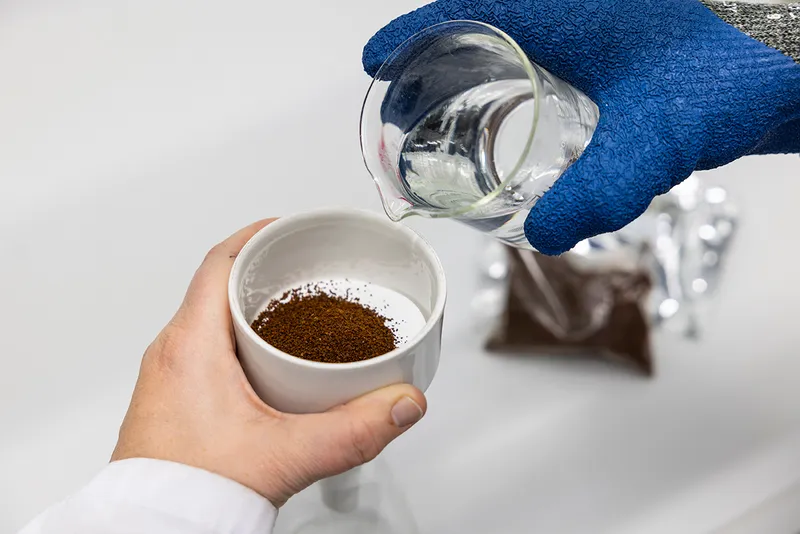 Person pours water into the grounded up cell-based coffee