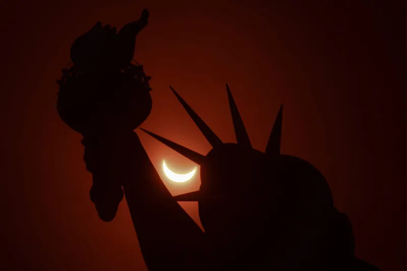 Partial solar eclipse seen through spikes of the Statue of Liberty.
