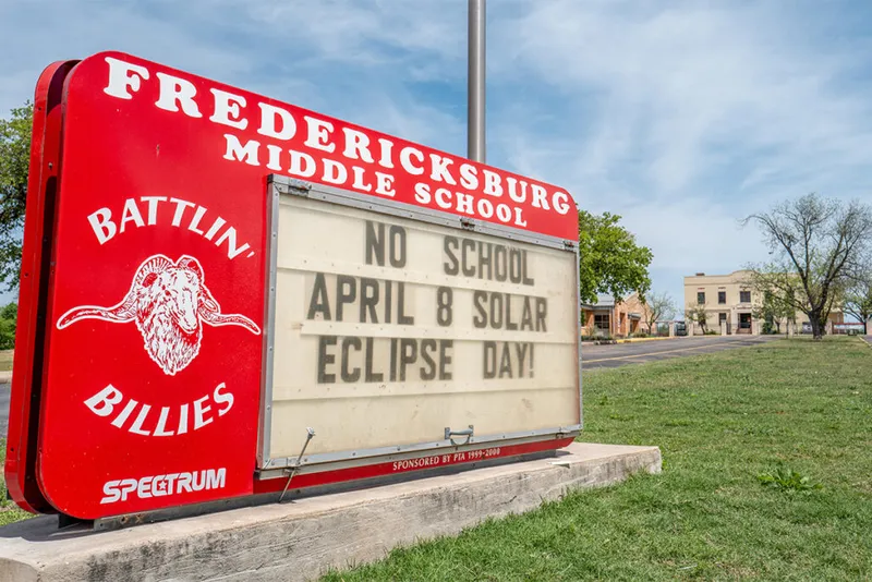 Sign with school closure eclipse message.
