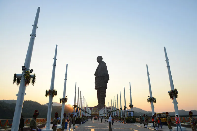 Huge statue of man against sunset.
