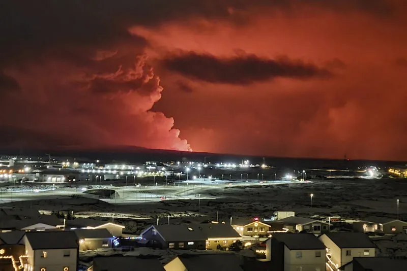 Smoke billows from a volcano making the sky glow red.