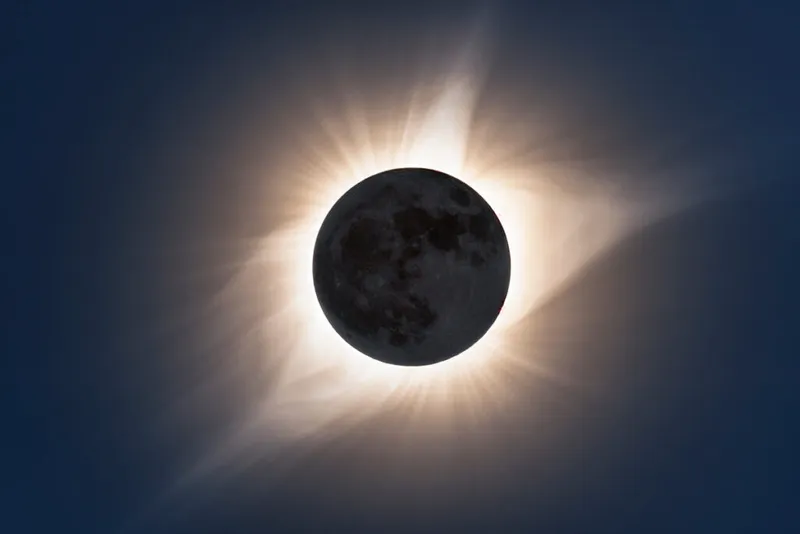 A dark circle is central in the frame surrounded by a wispy white halo.