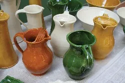 A selection of orange, mustard, green and white clay jugs found at a brocante in France
