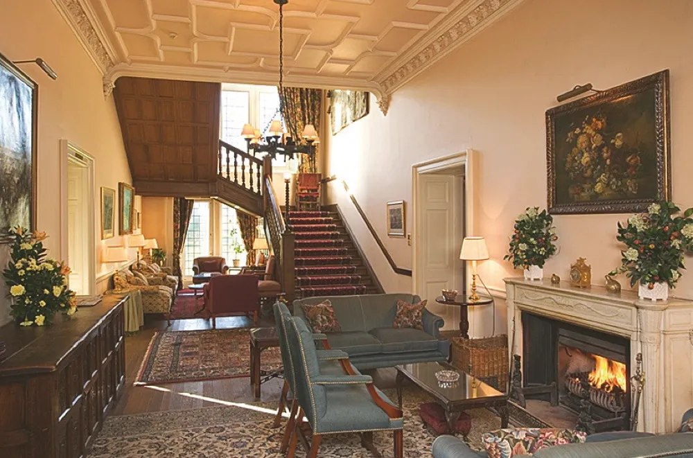 The entrace of the Ballathie House Hotel in Perthshire featuring a sweeping staircase and antique blue sofas