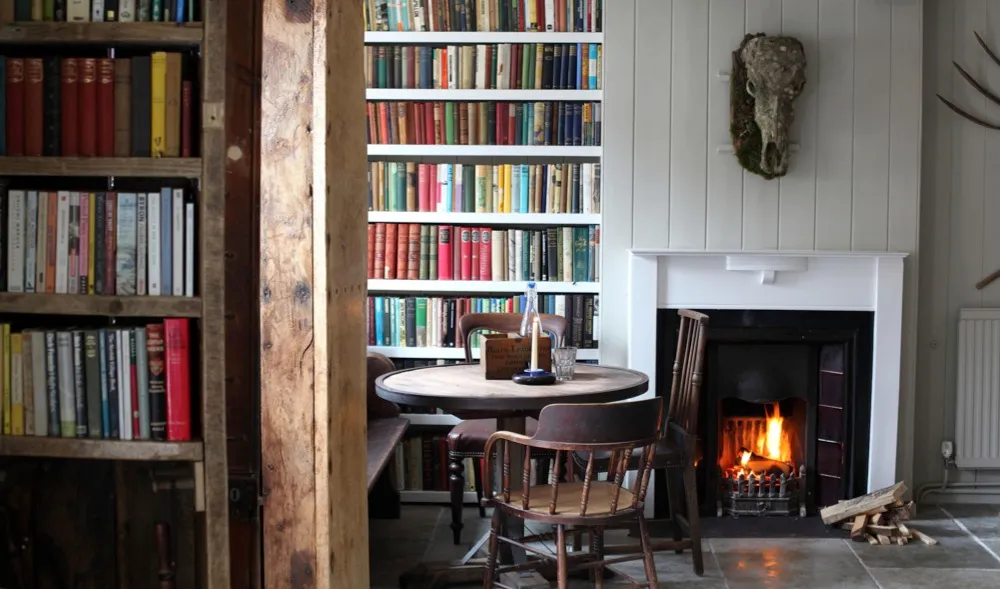 The interior of the Black Lion feating a bookshelf and a roaring fire