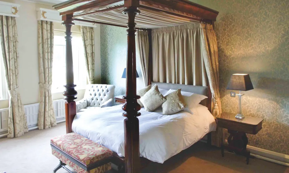 A bedroom at Grays Court featuring a brown four-poster bed and floral wallpaper