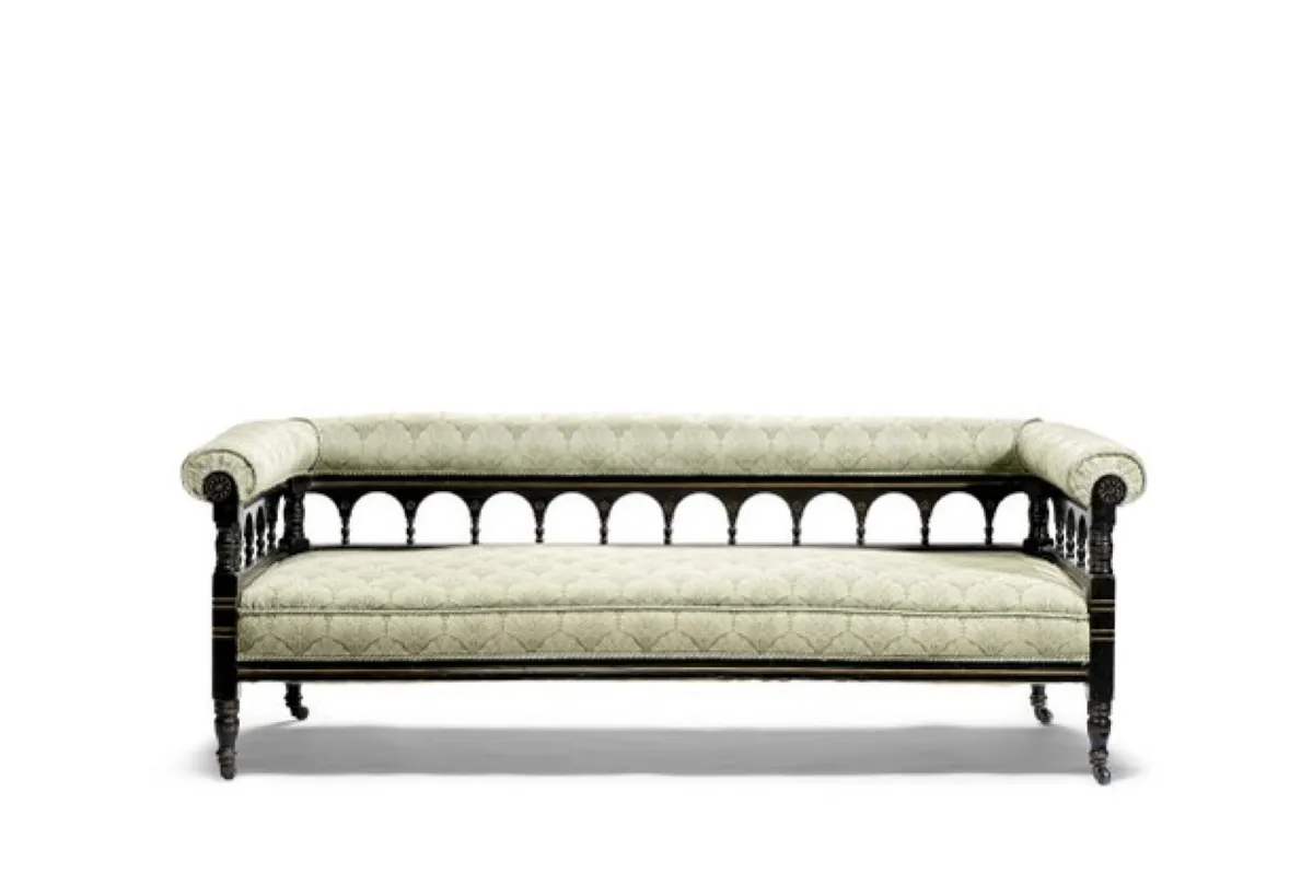 An antique sofa with pale cream cushions and a cut-out back