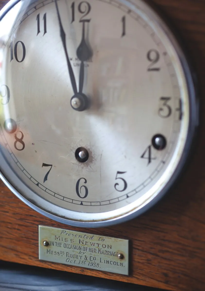 The face of the clock. A metal tag reads 'Presented to Miss Newton, on the occasion of her marriage, Oct. 1st 1938'