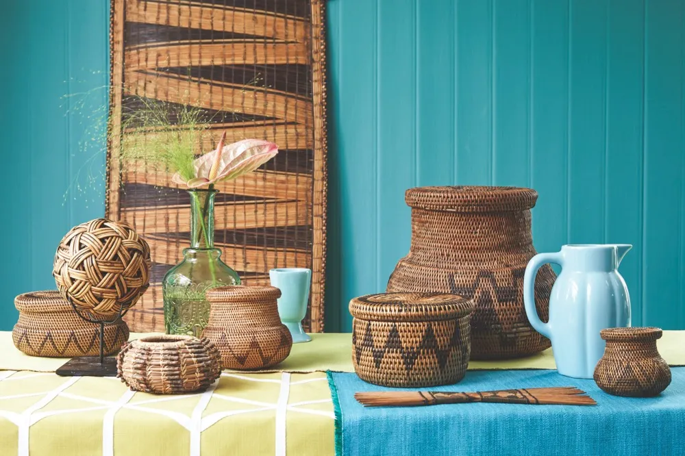 A table with a lime green and blue table cloth adorned with woven rattan bowls, baskets and panels