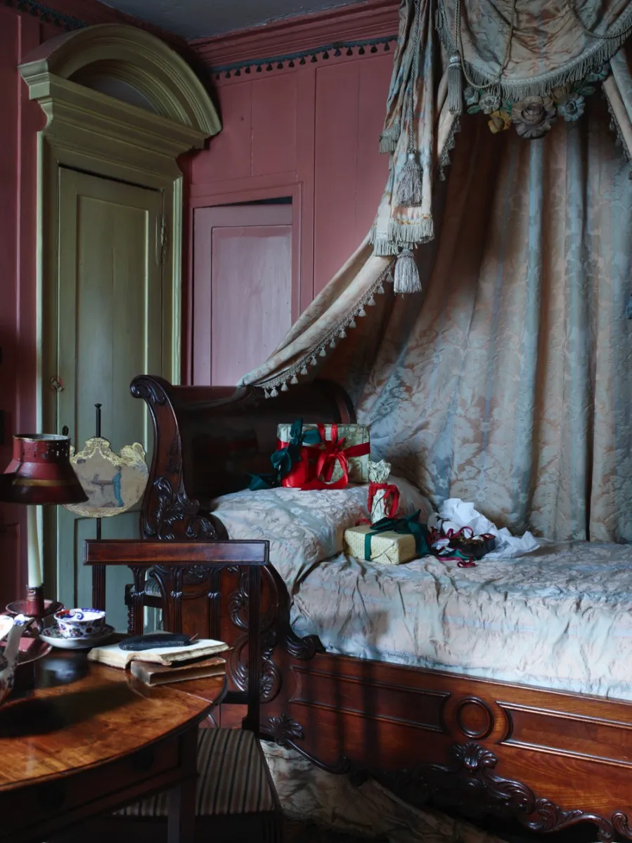 A bedroom in Dennis Severs' House with a mahogany single bed swathed in a damask-printed canopy