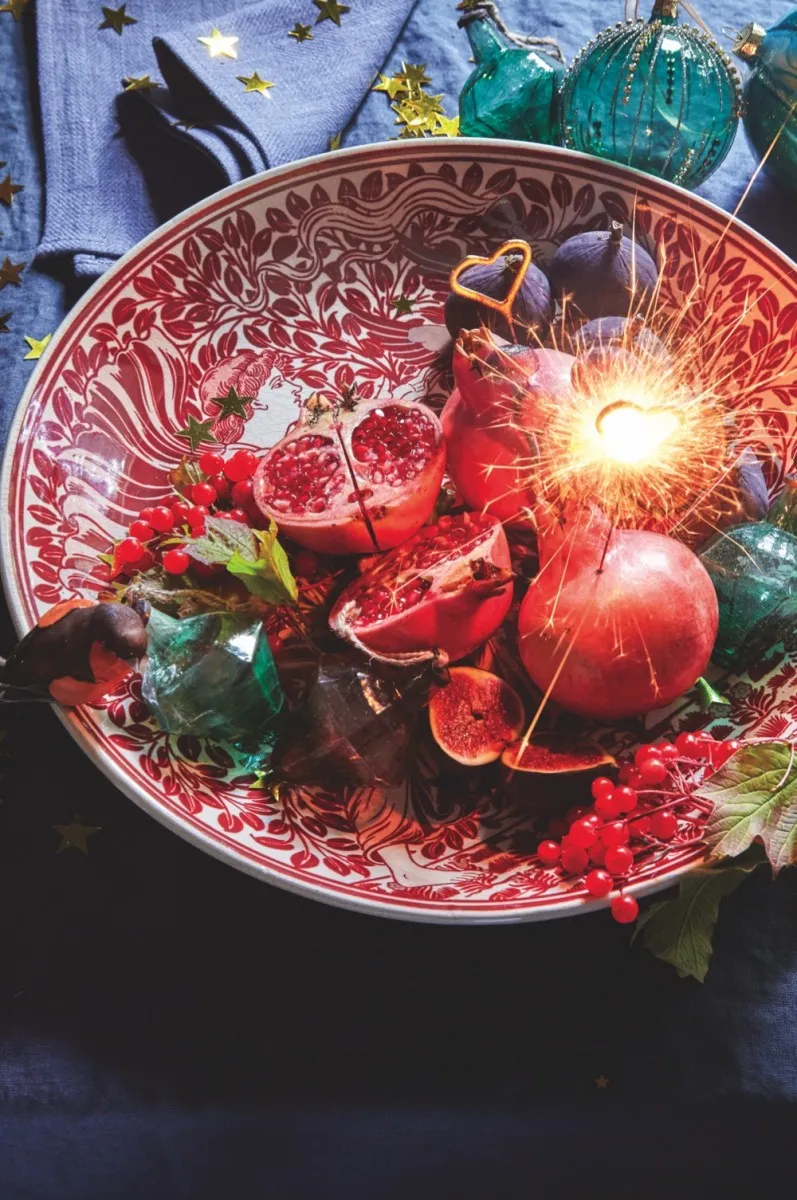 A red and white William de Morgan charger holds festive fruits and joyful sparklers