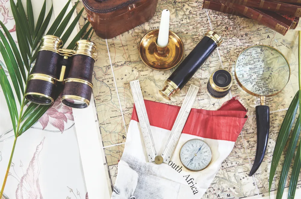 Binoculars, a map, a compass, and other various essential explorer's items sat on a map