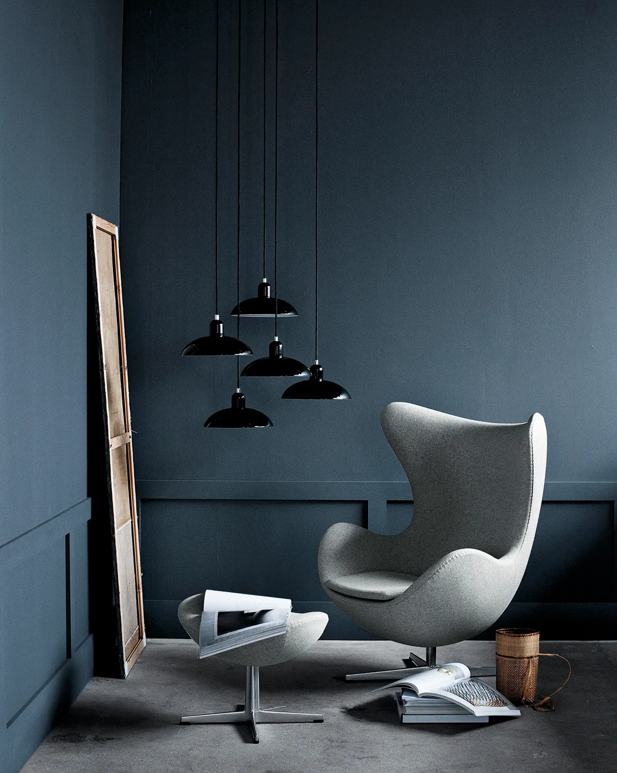 An Egg Chair upholstered in grey fabric against a dark blue wall